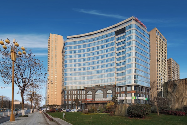 Un hotel moderno con fachada curva, varios pisos y un llamativo letrero 'Hampton'.