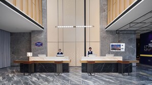 A hotel reception area with two reception desks, marble flooring, wooden paneling on the walls, and a large screen displaying a hotel image.