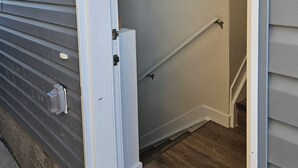 A narrow entryway with a wooden floor, a white door, and a light fixture on the wall. - Your home away from home—comfortable, and calm. proximity to popular attractions (Edmonton)
