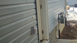 A house exterior with a door, a small step leading to the entrance, and outdoor electrical boxes. - Your home away from home—comfortable, and calm. proximity to popular attractions (Edmonton)