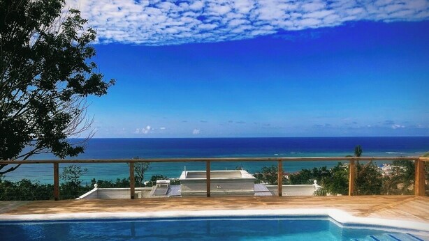 Una piscina con vista al océano y una terraza de madera.