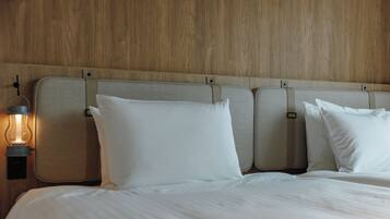 Een bed met wit beddengoed, een hoofdbord met een lamp en een houten wand.
