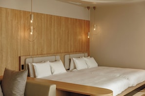 Camera d'albergo moderna con un poggiatesta in legno, un letto grande con biancheria bianca e un comodino in legno.