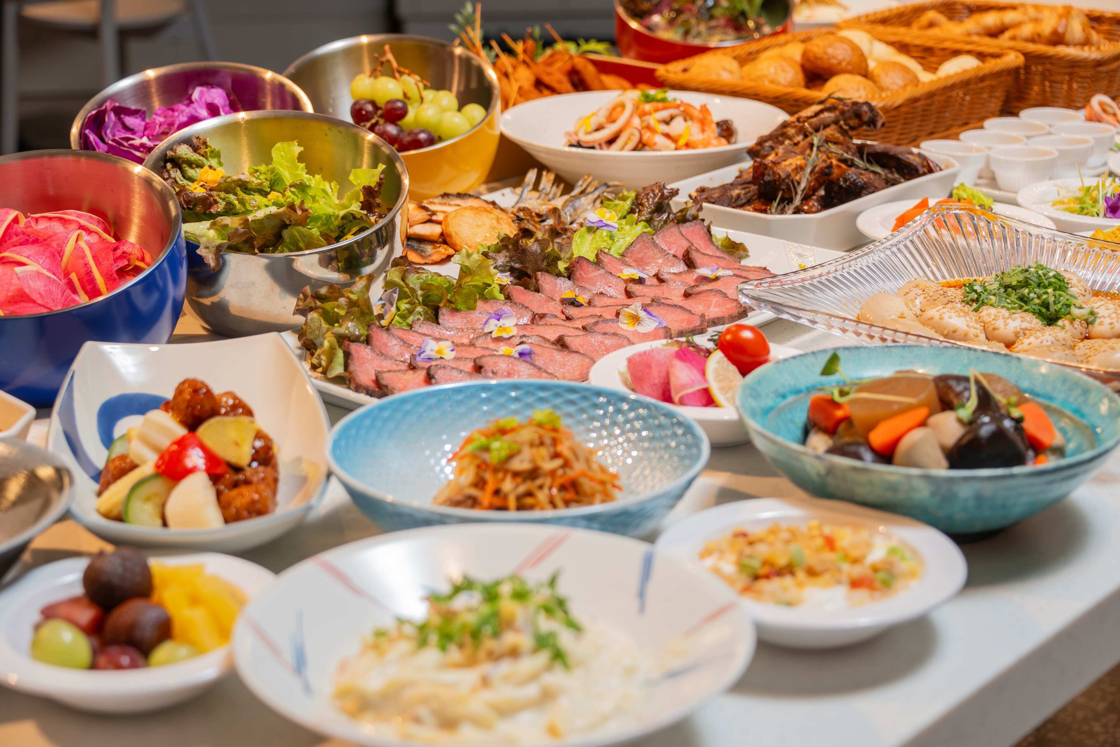 A buffet table with various dishes including meats, salads, and desserts.