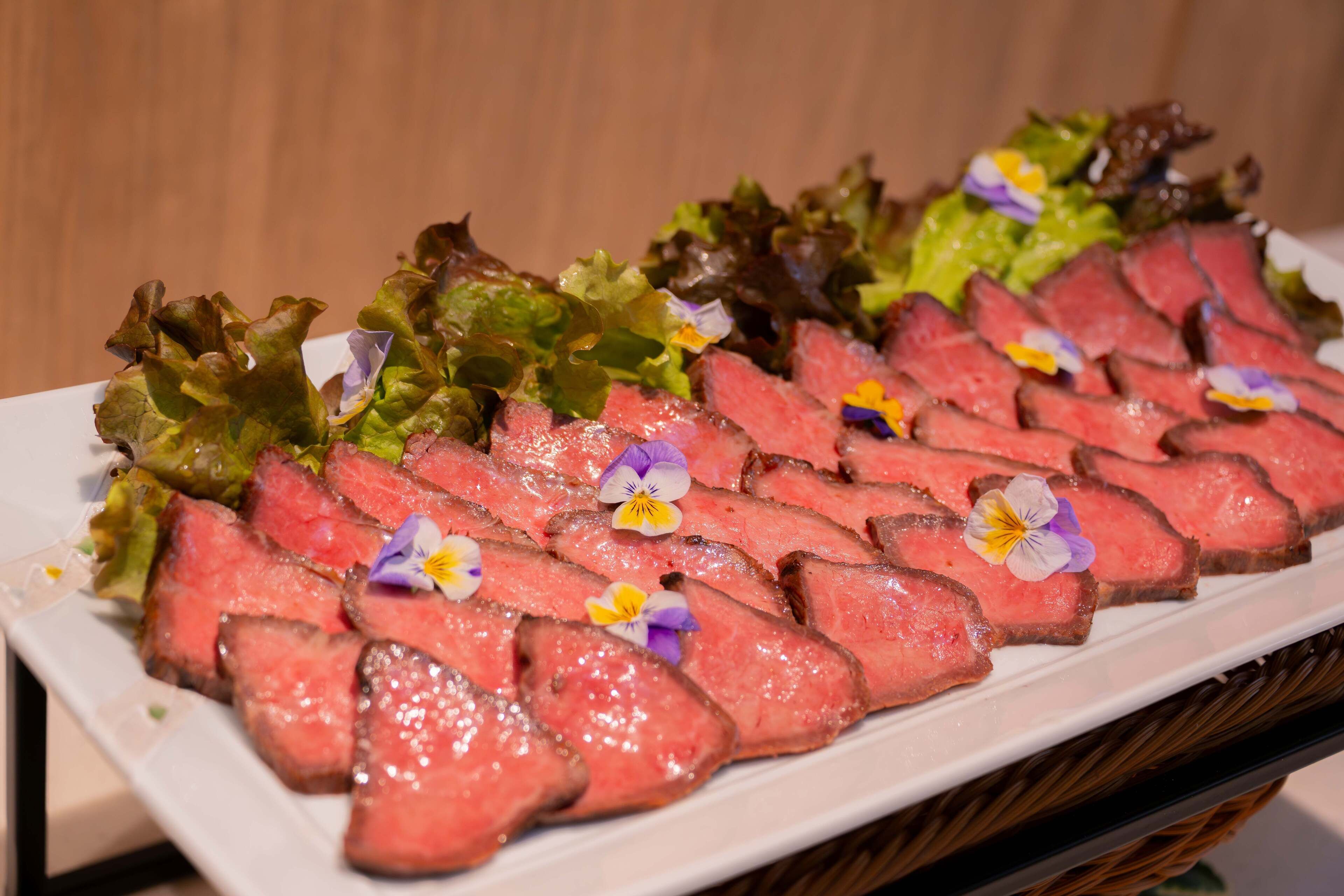 A plate of sliced meat with flowers on a white plate.