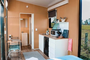 Una habitación compacta con kitchenette, una cama, una mesita y una ventana con vistas al exterior.