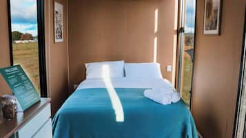 A hotel room with a bed, a window, a wall-mounted air conditioner, and a welcome sign.