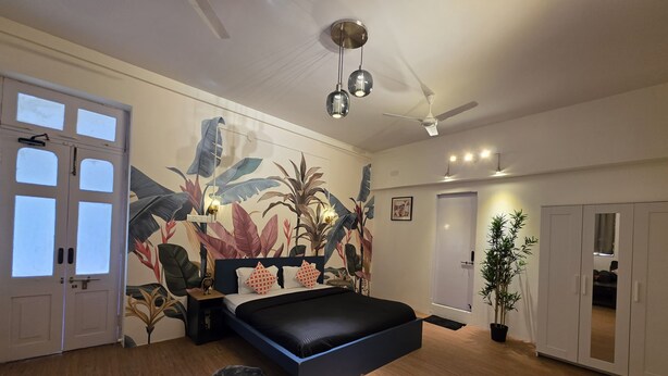 Une chambre à coucher moderne avec un grand lit, un ventilateur de plafond et une fresque murale.