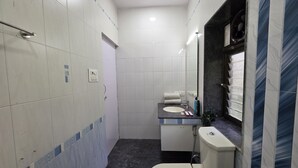 Une petite salle de bain aux dimensions réduites, avec des carreaux blancs, un lavabo blanc, des toilettes et un miroir.