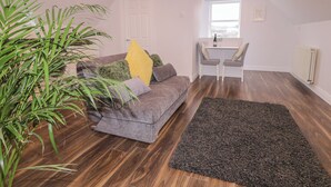 A cozy living room with a grey sofa, a black rug, and a potted plant. - The Loft - 96B (Coleraine)