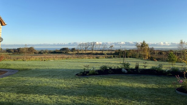 A grassy field with a building on the left and a clear sky. - The Loft - 96B (Coleraine)