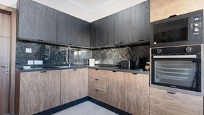 Een moderne keuken met donkere houten kastjes, een zwart aanrecht en een inbouwoven.