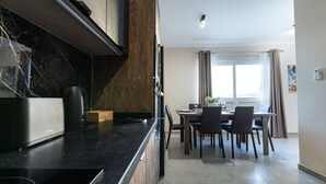 Een moderne keuken met een zwart aanrecht, houten kastjes en een eethoek met een tafel en stoelen.