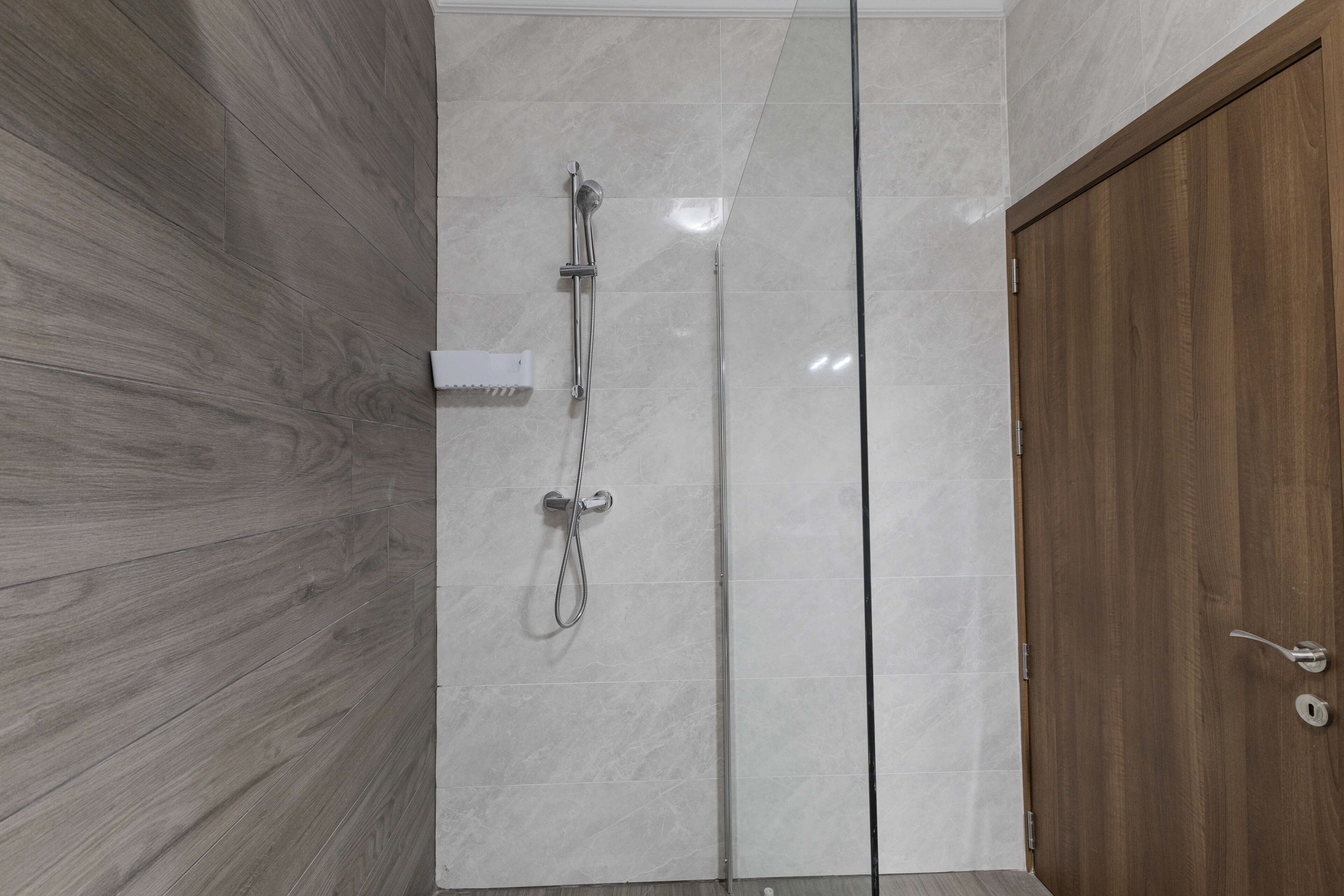 A modern bathroom with a glass shower enclosure, a wooden door, and a towel rack.