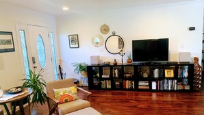 A living room with a wooden floor, a bookshelf, a television, and a chair with a cushion. - Indoor/Outdoor Living in Sonoma Valley (Sonoma)