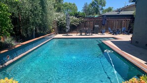 A rectangular swimming pool with clear blue water, surrounded by a wooden deck and potted plants. - Indoor/Outdoor Living in Sonoma Valley (Sonoma)