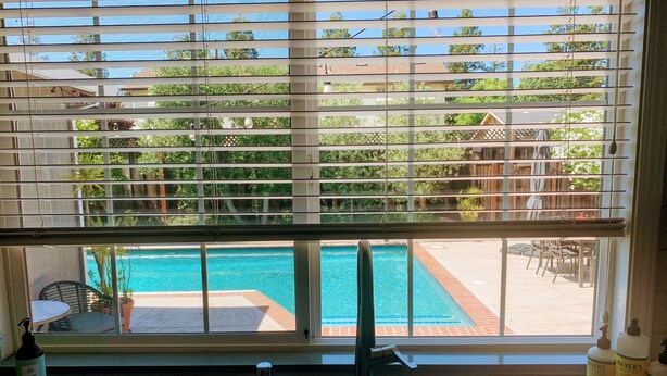 A kitchen with a view of a swimming pool through a window with blinds. - Indoor/Outdoor Living in Sonoma Valley (Sonoma)