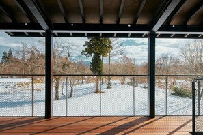 A covered outdoor area with a wooden deck and a metal fence. - Villa El Cielo Myoko (Myoko)