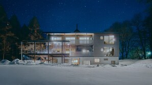 Een modern huis met twee verdiepingen, grote ramen, een balkon en een schoorsteen.