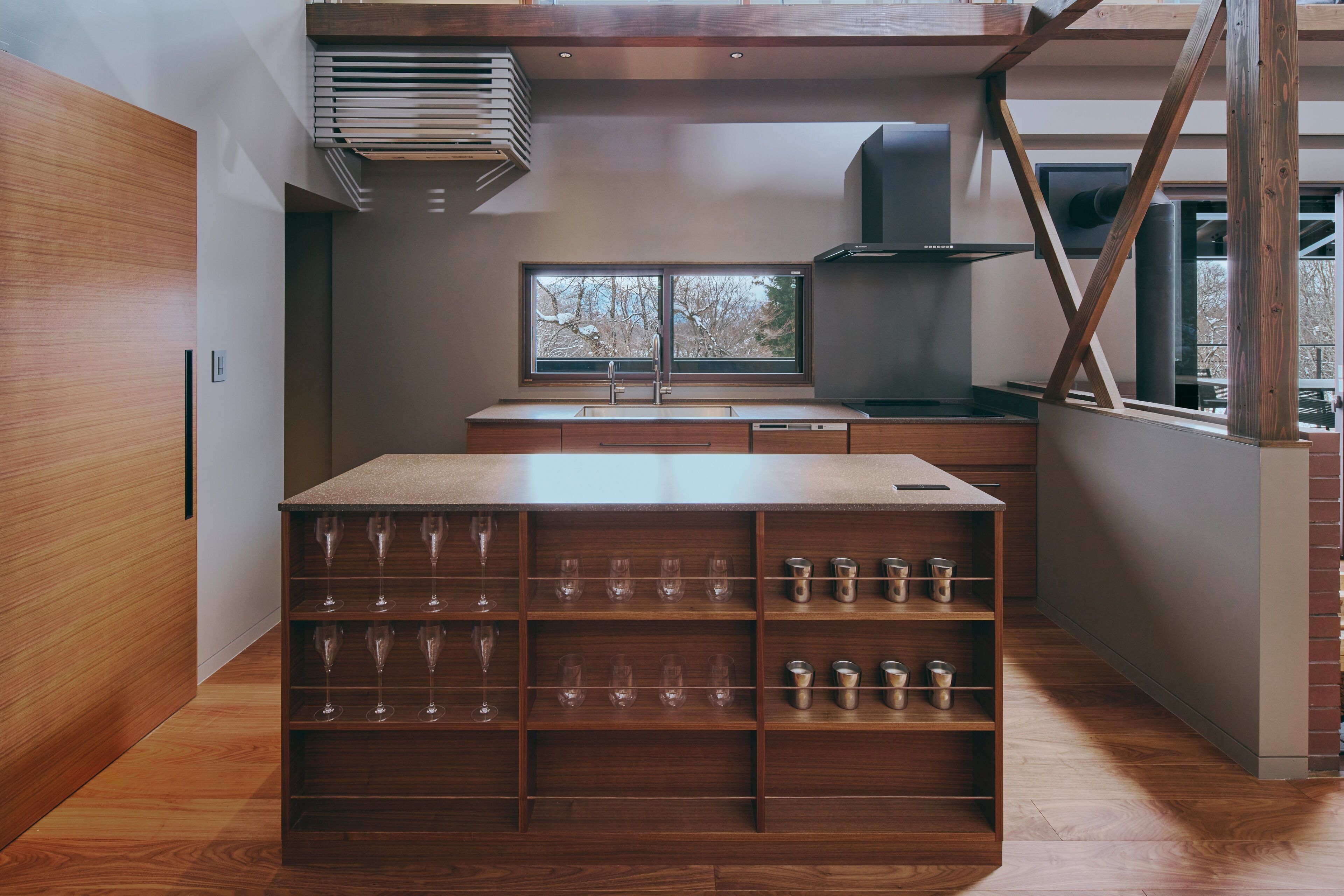 A modern kitchen with wooden cabinetry, a built-in wine rack, and a large window providing a view of the outdoors.
