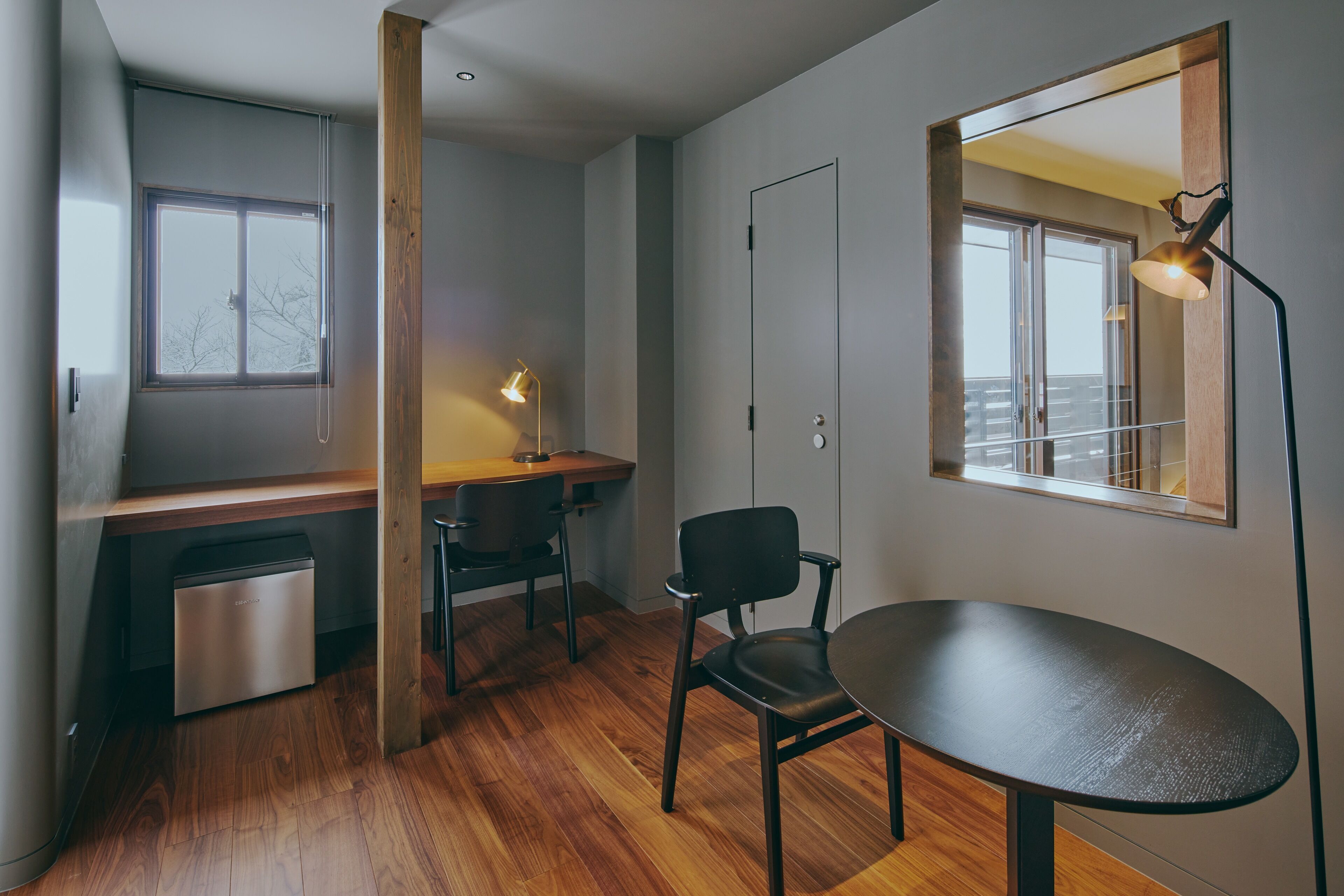 Una habitación moderna y funcional con un escritorio de madera, una silla, una mesa de comedor y horno empotrado.