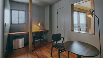 Una habitación moderna y funcional con un escritorio de madera, una silla, una mesa de comedor y horno empotrado.