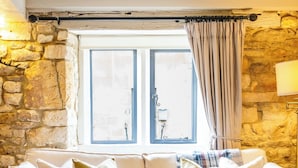 Ett mysigt vardagsrum med en beige soffa, ett soffbord i glas och en färgglad pläd på golvet.