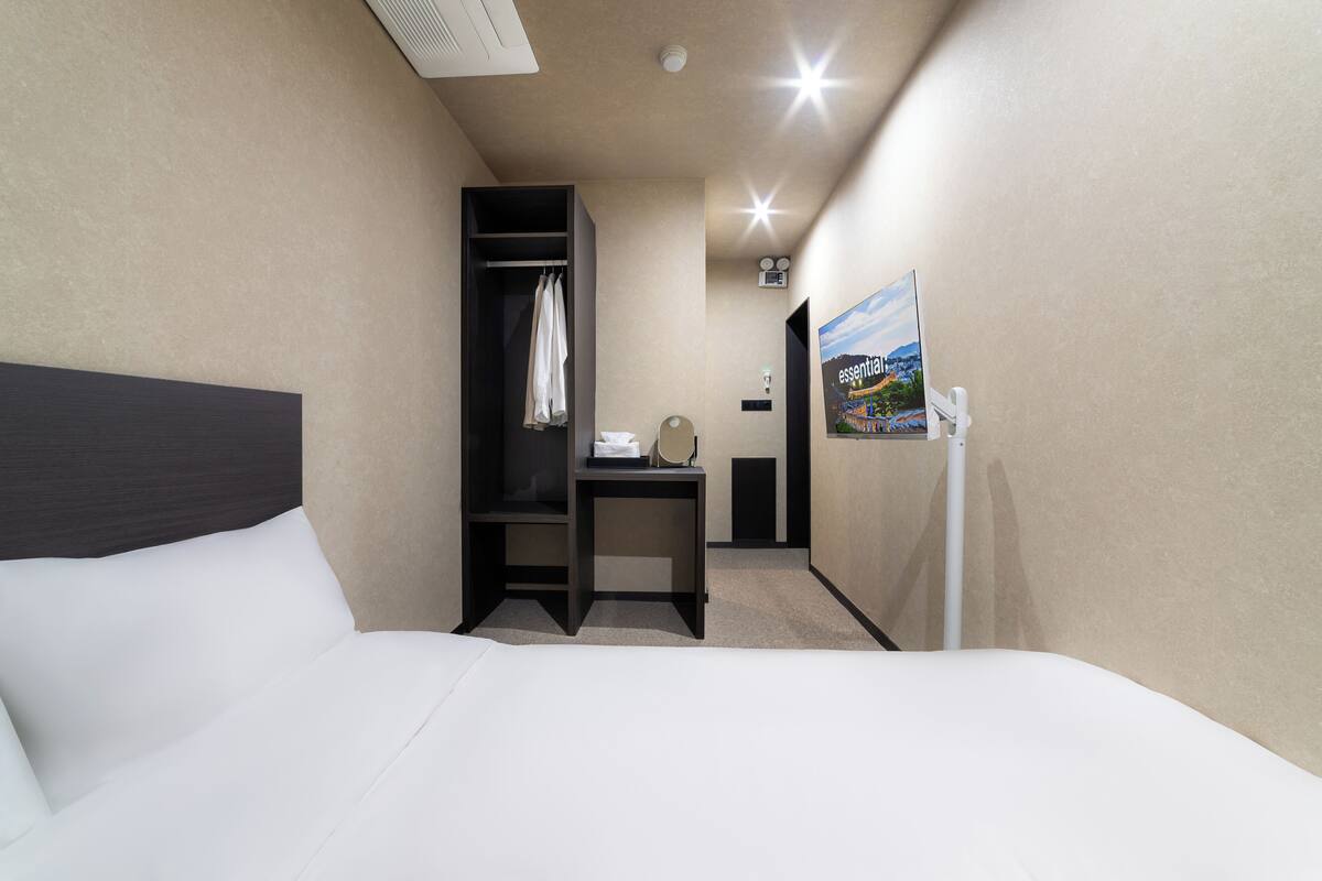 Ein Hotelzimmer mit Bett, Schreibtisch, Stuhl, Kleiderschrank und einem Bild an der Wand.