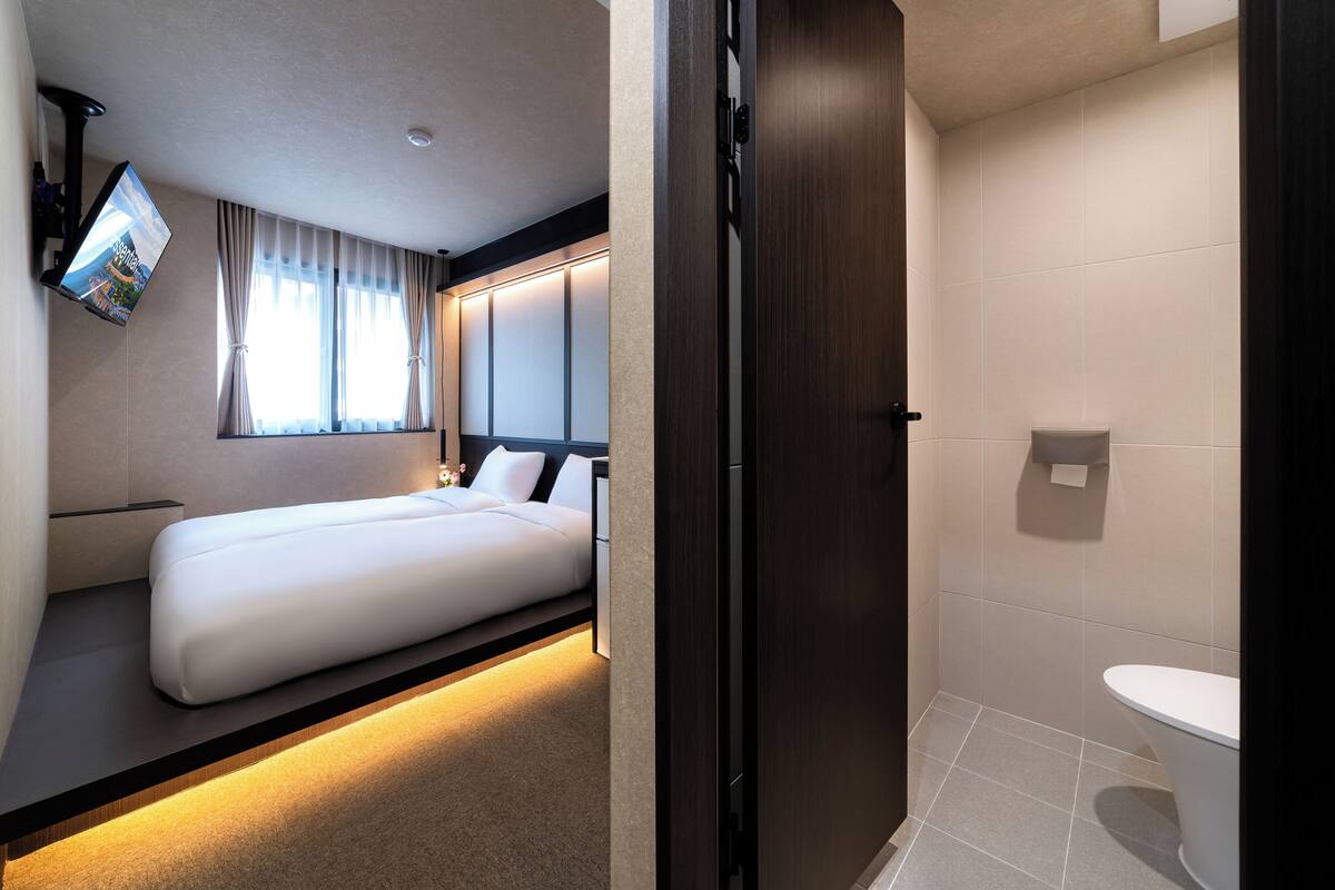Ein Hotelzimmer mit Bett, Wandfernseher und Badezimmer mit Toilette und Waschbecken.