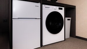 Ein kompakter Waschraum mit einem weißen Winia-Kühlschrank, einer LG-Waschmaschine und einem Mülleimer.