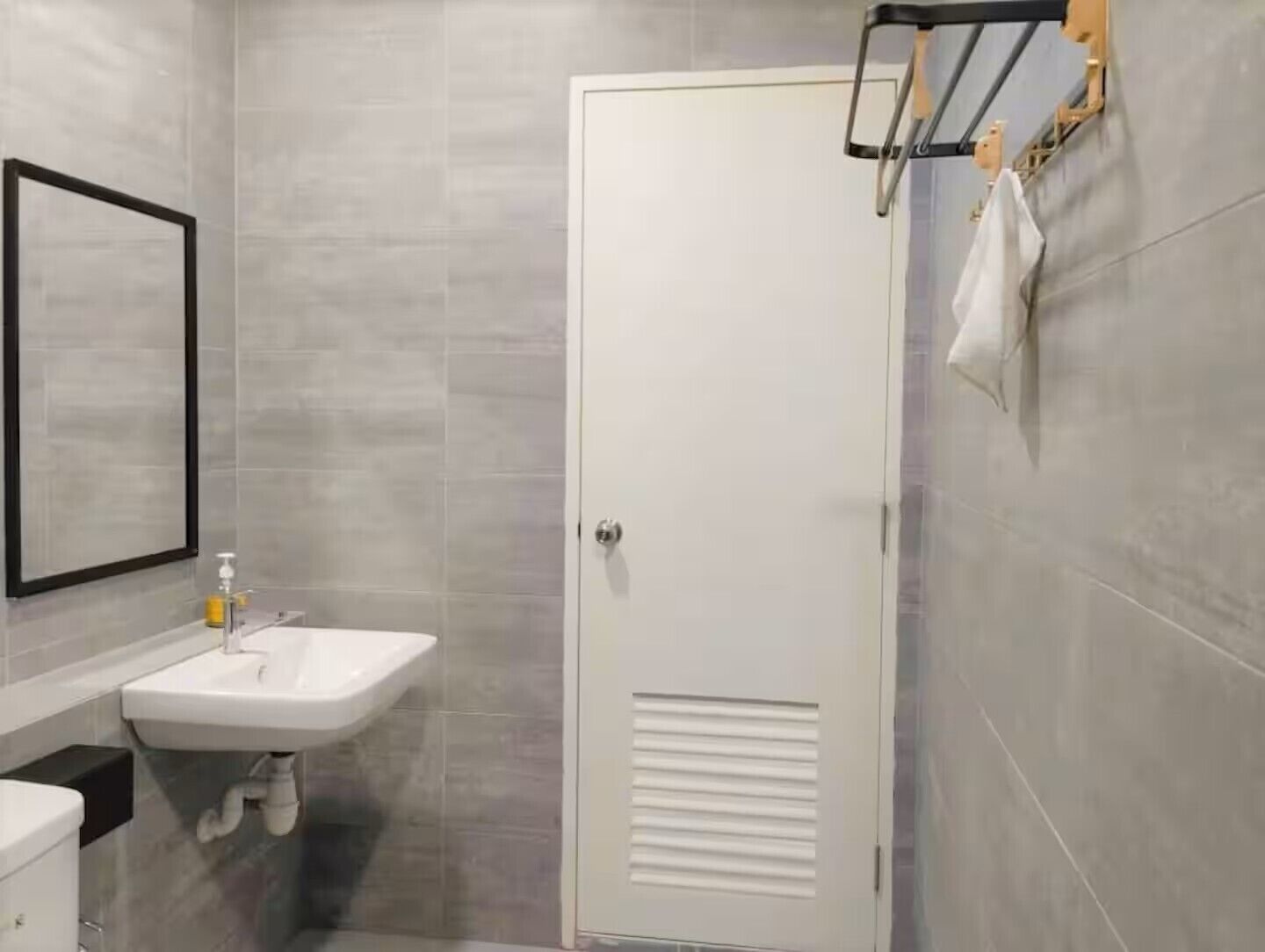 A modern bathroom with a white sink, a toilet, and a door with a towel rack.