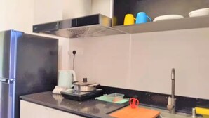 A modern kitchen with a black countertop, stainless steel sink, and a range hood. - Spacious Riverview Suite @Kuching Riverine Resort (Kuching)