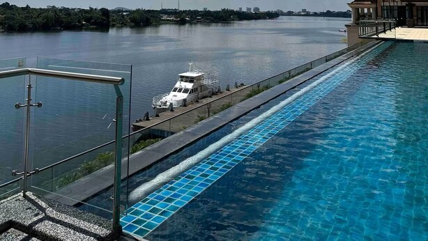A swimming pool with a view of a body of water and a distant city skyline. - Spacious Riverview Suite @Kuching Riverine Resort (Kuching)