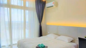 A hotel room with a large bed, a bedside table, a chair, and an air conditioning unit. - Spacious Riverview Suite @Kuching Riverine Resort (Kuching)