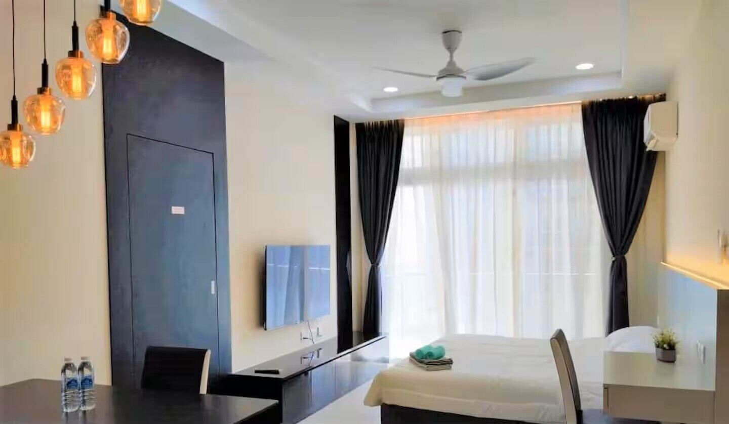 A modern hotel room with a bed, a desk, a chair, a TV, and a ceiling fan.