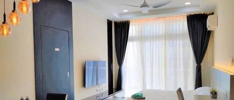 A modern hotel room with a bed, a desk, a chair, a TV, and a ceiling fan.