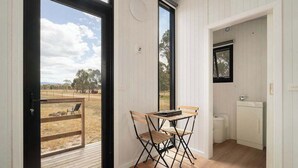Una habitación con una mesa y sillas de madera, una ventana y vistas al exterior.