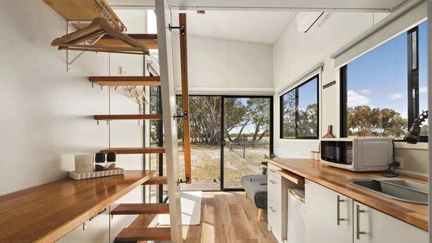 Una cocina moderna con encimeras de madera, microondas integrado y un amplio ventanal con vistas al exterior.