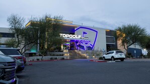 Moderni rakennus, jonka julkisivussa on suuri, huomiota herättävä kyltti, jossa lukee: ”TOPGOLF TOPTRACER”.
