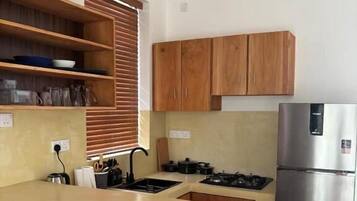 Una cocina moderna con armarios de madera, una isla central, estufa integrada y un refrigerador de acero inoxidable.