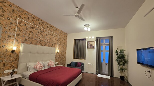 A bedroom with a bed, a ceiling fan, a TV, and a plant. - Studio Apartment 103 In Malabar Hill By Florastay (Mumbai)