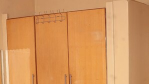 Une pièce avec une grande armoire en bois, un lit et un mur blanc.