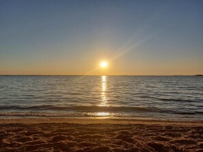 Una playa con el sol reflejándose en el agua.