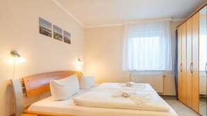 Une chambre d’hôtel avec un lit en bois, deux lampes de chevet, une fenêtre avec des rideaux et un radiateur.