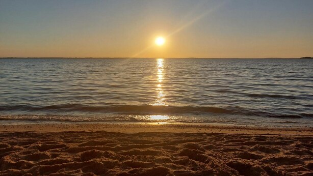 Une plage où le soleil se reflète sur l’eau.