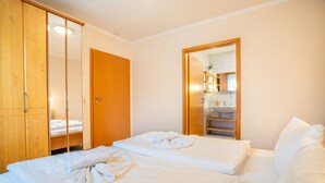 A hotel room with a bed, a wardrobe, and a bathroom visible through an open door. - Cozy 2-Room Apartment on Usedom Island, Ground Floor, Perfect for 2 to 4 Guests (Pudagla)