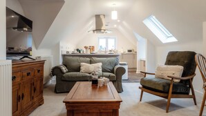 Ein gemütliches Loft mit Küche, einem Wohnbereich mit Sofa und Sesseln sowie einem Esstisch.
