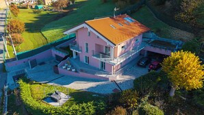 Une maison à plusieurs étages, dotée d’un toit en pente, d’un balcon et d’un petit jardin.
