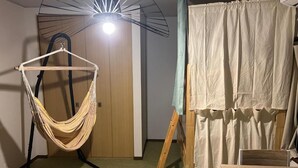 Huoneessa on riipputuoli, puinen maalausteline ja pöytä.