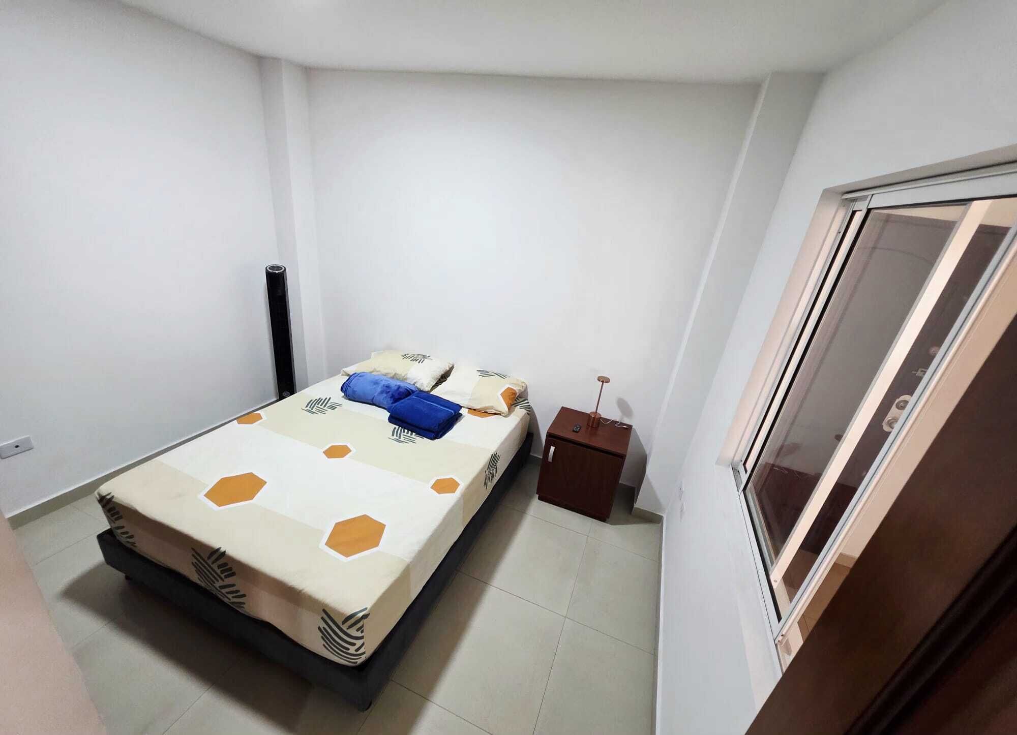 Un dormitorio pequeño y ordenado, con cama, mesita de noche y armario.